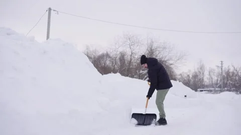 A man throws snow with showel on a high snowdrift Stock Footage 328647441