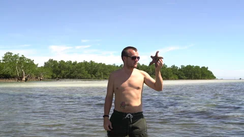 Man throws Starfish into the sea Stock Footage 91883109