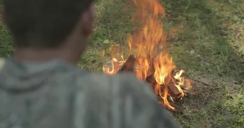 Man throws stick into campfire in the forest Stock Footage 76703322