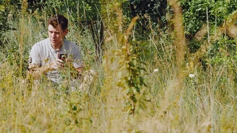 A man throws a stick German shepherd in the meadow and looks at the smartphone Stock Footage 111656732