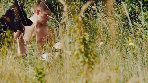 A man throws a stick German shepherd in the meadow and looks at the smartphone Stock Footage 111657443