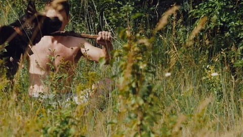 A man throws a stick German shepherd in the meadow and looks at the smartphone Stock Footage 111657791