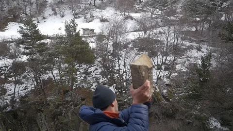 Man throws a stone from the mountain down Stock Footage 87791156