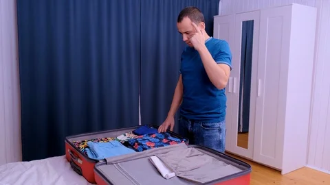 A man throws things from the closet into a travel suitcase. Stock Footage 123712618