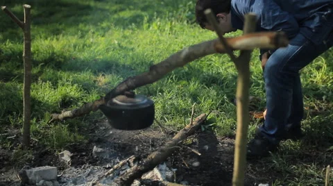 Man throws wood on the fire in the camping. Early morning in the forest Stock Footage 64324843