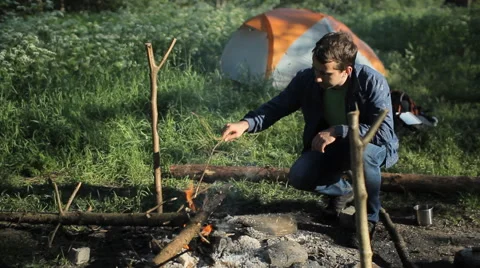 Man throws wood on the fire in the camping. Early morning in the forest Video stock 64325053