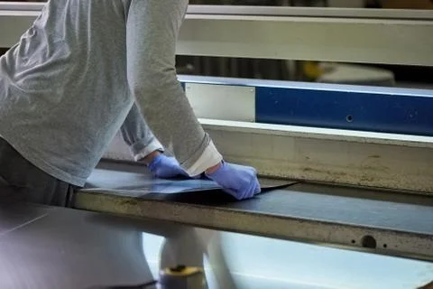 Man is thrusting a metal sheet in a slit. Stock Photos