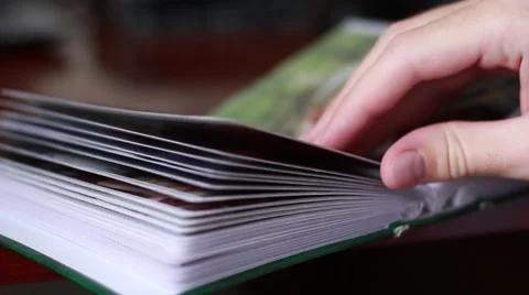 Man thumbs through an old photo album Vídeo Stock 65370574