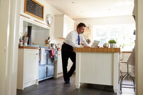 Man in tie in kitchen using laptop, full length, low angle Stock Photos