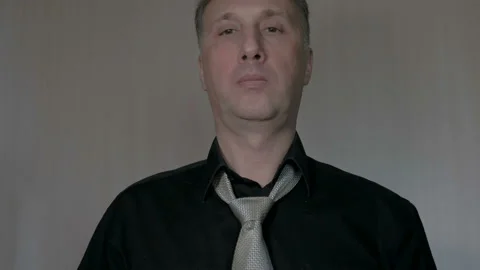 A man tie a knot on a tie. Going to work. Black shirt. Video stock 85875482