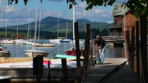 A man ties his boat to a wooden dock on a rural lake in Central Stock Footage