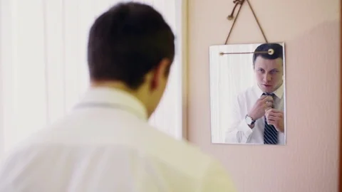 Man ties up tie in front of mirror Stock Footage 76992850