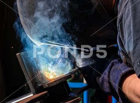 Man tig welding steel plates with brilliant bright white star burst blooms Stock Photos