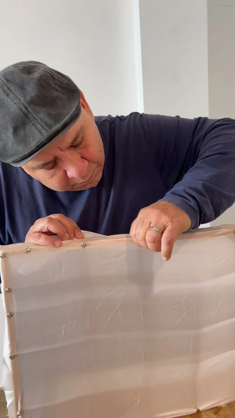 Man tightening the silk on the frame in silk painting workshop Stock Footage 330611748