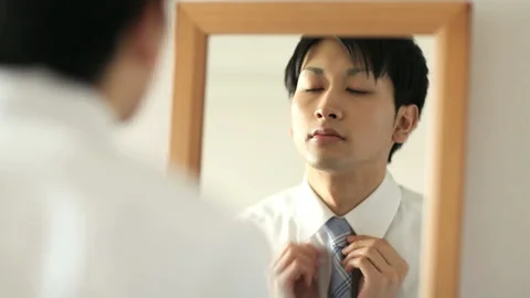 A man tightening a tie while looking at the mirror Stock Footage 159806334