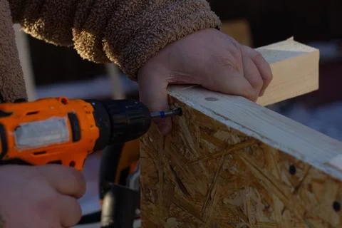 A man tightens a screw with a screwdriver. A close-up of a mans hands holding an Stock Photos