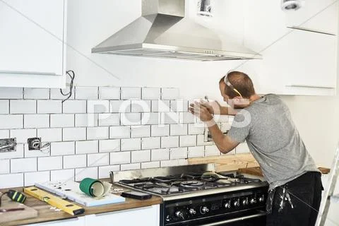 A Man Tiling A Kitchen Wall
