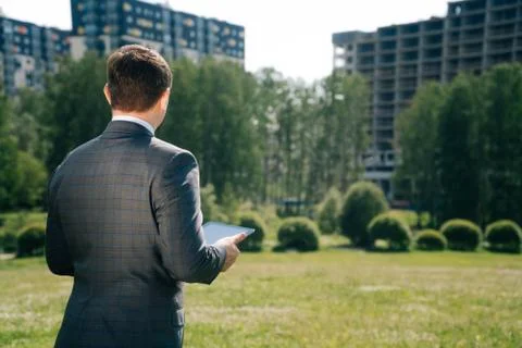 A man with tilted jacket suit stands with his back somtrit on the constructio Stock Photos