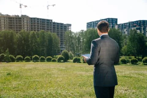 A man with tilted jacket suit stands with his back somtrit on the constructio Stock Photos