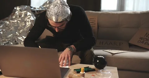A man in a tinfoil hat draws esoteric signs. Conspiracy theory. 库存影片 272252453