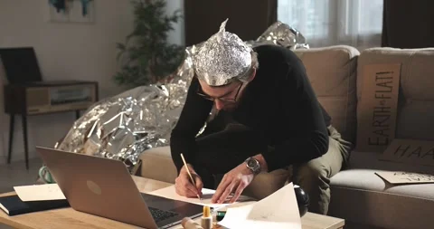 A man in a tinfoil hat draws esoteric signs. Conspiracy theory. Stock Footage 272252565