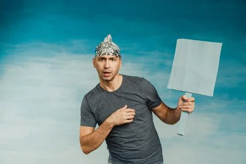 A man in a tinfoil hat scaredly grabs his hands with his hands wide open his  Stock Photos