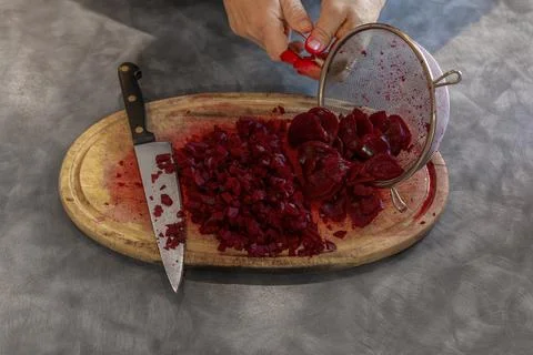 Man Tipping Sliced Beetroot from Strainer onto Oval Wooden Cutting Board Stock Photos