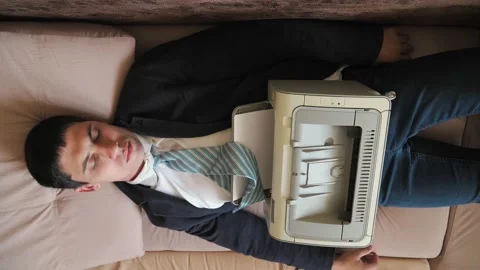 Man tired after work sleeps in bed in office clothes printer prints 動画素材 131339450