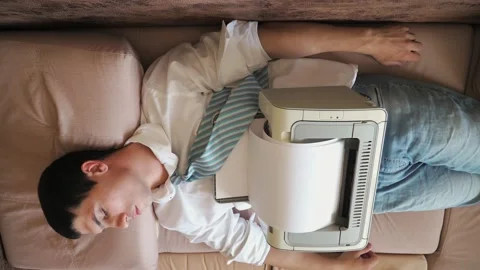 Man tired after work sleeps in bed office clothes he has printer on and prints 動画素材 132015877