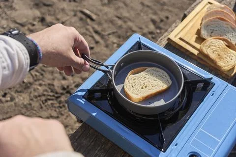 Man toasts bread outdoors, using a frying pan on a portable stove, for brea.. Stock Photos