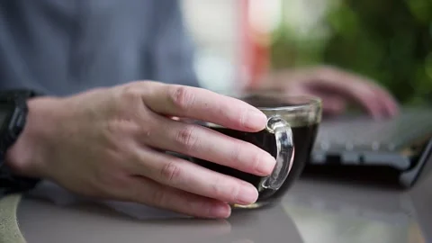 Man took a coffee or tea for a drink on his work desk with a laptop  Stock Footage 167811248