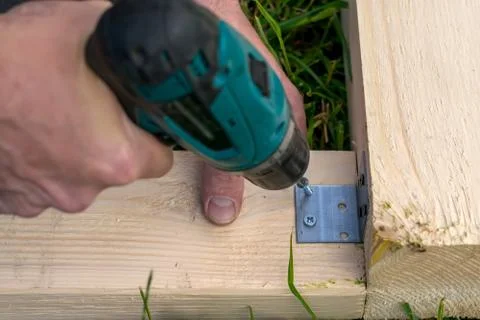 Man, tool, drilling screw into the construction of the boards on the grass Stock Photos