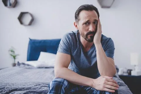 Man with toothache sitting on bed Stock Photos