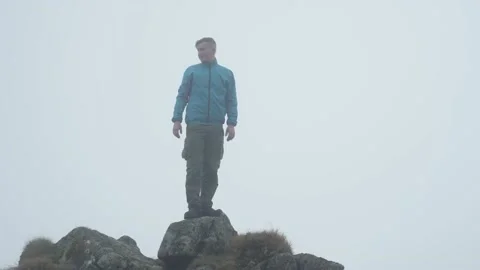 A man on top of a cliff in cloudy weather. The boy conquered the mountain Stock Footage 218438813