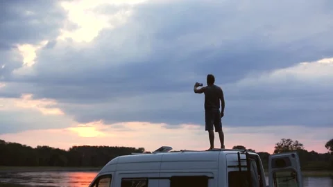 Man on top of his camper van taking a photo with smartphone Stock Footage 135381503