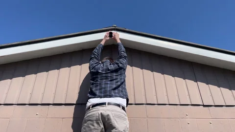 Man at the top of a ladder adjusting a security ladder Stock Footage 288811299