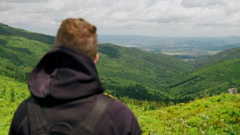 Man on top of the mountain looking at beautiful nature, scenic landscape 4K. Stock Footage 234569507