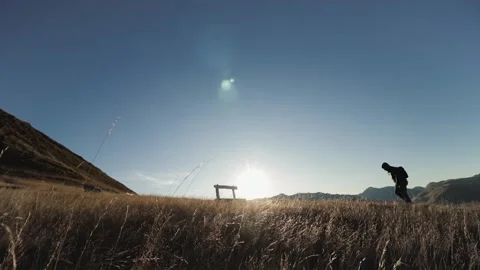 A man on top of a mountain sits on a bench at sunset Stock Footage 133928861