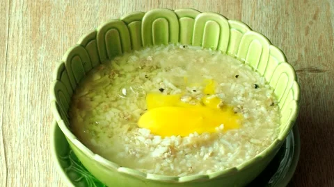 Man is toping egg and spring onion on porridge, Thai morning food. Stock Footage 203482360