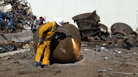 Man torch cutting large scrap metal in junkyard in slow motion Stock Footage 100836068