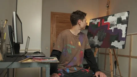 Man torn between passion and career stares at canvas then computer confused Stock-Footage 313558790