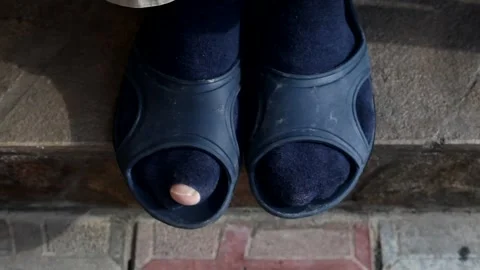 A man in torn socks and rubber slippers funny moves his finger. Stock Footage 130225113