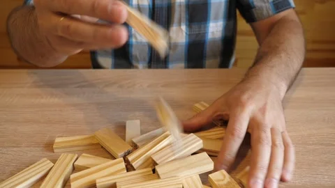 A man tosses wooden blocks that fall onto the table surface with a distinctiv Stock Footage 341254837