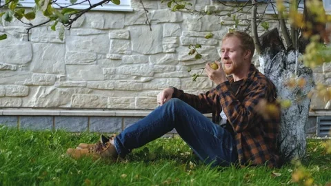 Man tossing an apple while sitting under a tree Stock Footage 200826284