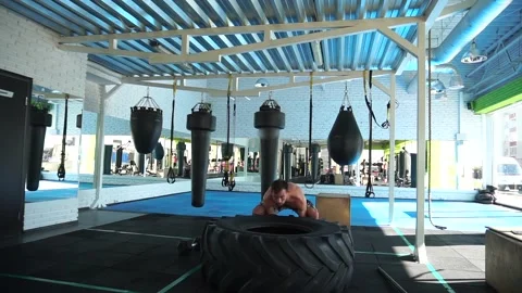 Man tossing a tyre during an intense workout session in a training space. Stock Footage 140124506