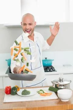 Man tossing vegetables at the kitchen Stock Photos