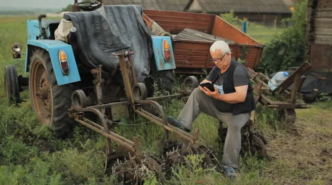 A man touch tablet near the tractor and move away. Agriculture surrounds Stock Footage 64587636