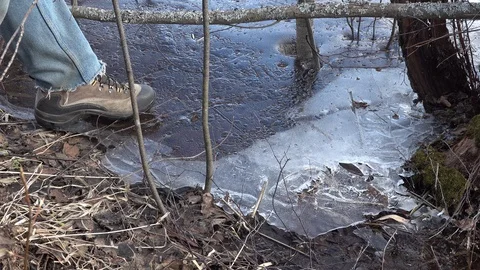 Man touches checks the thin ice and steps on it. Autumn or Spring. Ice breaks. Видео 129880633