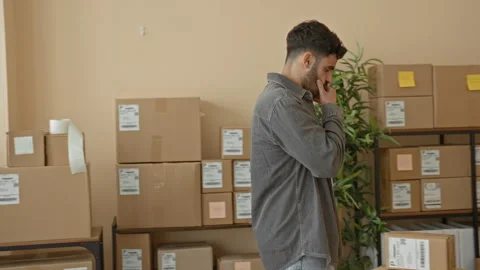 Man touches chin while inspecting stacked packages, labeled parcels and a l.. Stock Footage 337373388