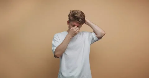 Man touches his face while standing against a plain wall in a minimalist se.. Stock-Footage 328247172